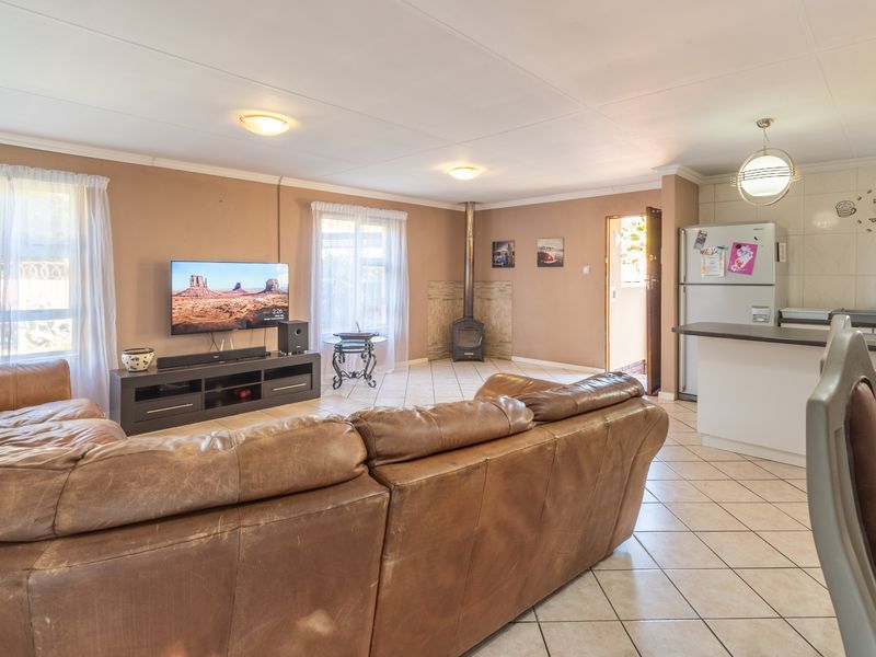 Spacious open-plan living area featuring tiled flooring, a cozy freestanding fireplace, and a functional kitchen with an island and ample cabinetry.