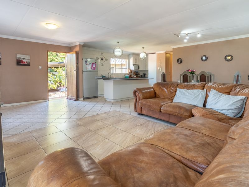 Spacious open-plan living area featuring tiled flooring, a wood-burning fireplace, and a functional kitchen with a central island and built-in cabinetry.