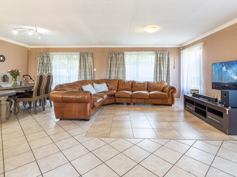 Spacious open-plan living and dining area featuring neutral wall tones, tiled flooring throughout, and large windows allowing for ample natural light.