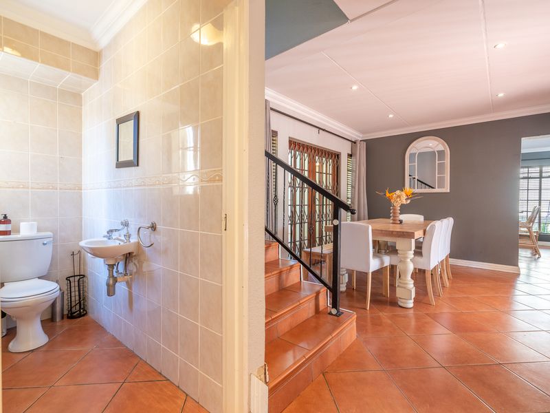 Open plan living and dining area featuring tiled flooring, recessed lighting, and an adjacent guest bathroom with a wall-mounted basin.