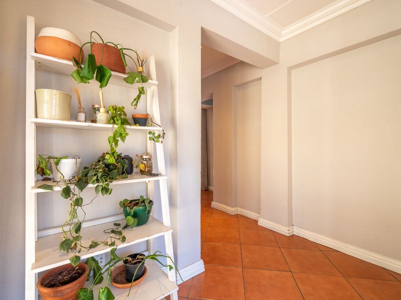 A bright hallway featuring neutral wall tones, classic crown molding, and durable ceramic tile flooring leading into the home.
