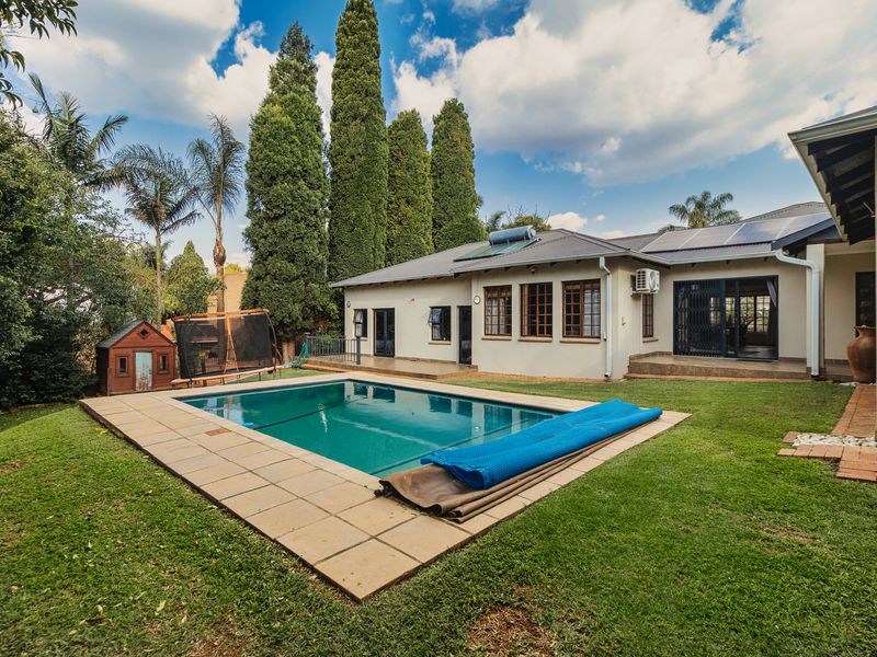 A well-maintained rear garden featuring a swimming pool with tiled surround, solar heating, and direct access to the home via sliding doors.