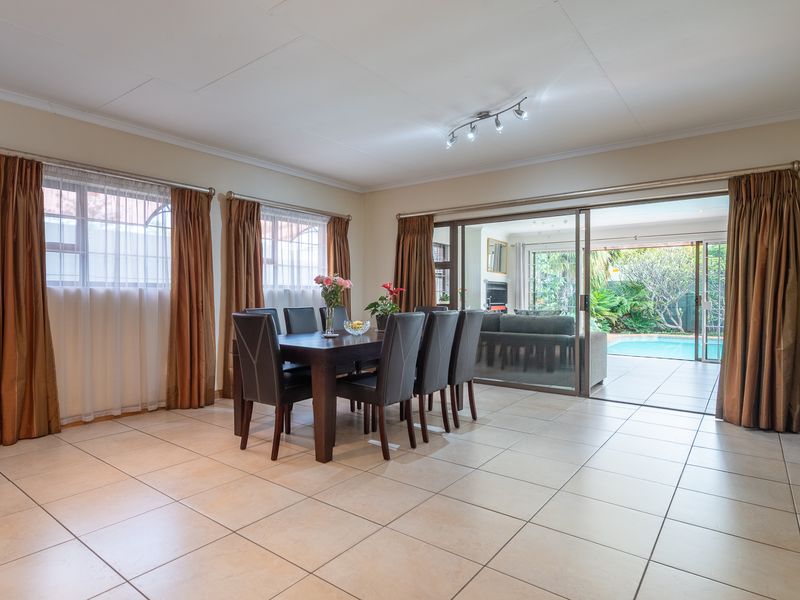 Spacious dining area featuring neutral tiled flooring and large sliding glass doors that provide seamless access to the outdoor patio and pool area.