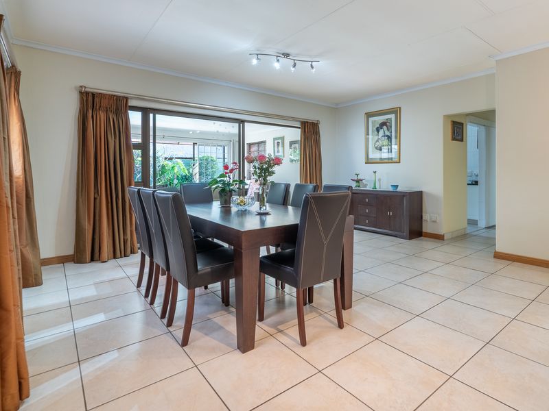 Spacious dining room featuring neutral tiled flooring, modern track lighting, and large sliding glass doors that provide access to the outdoor area.
