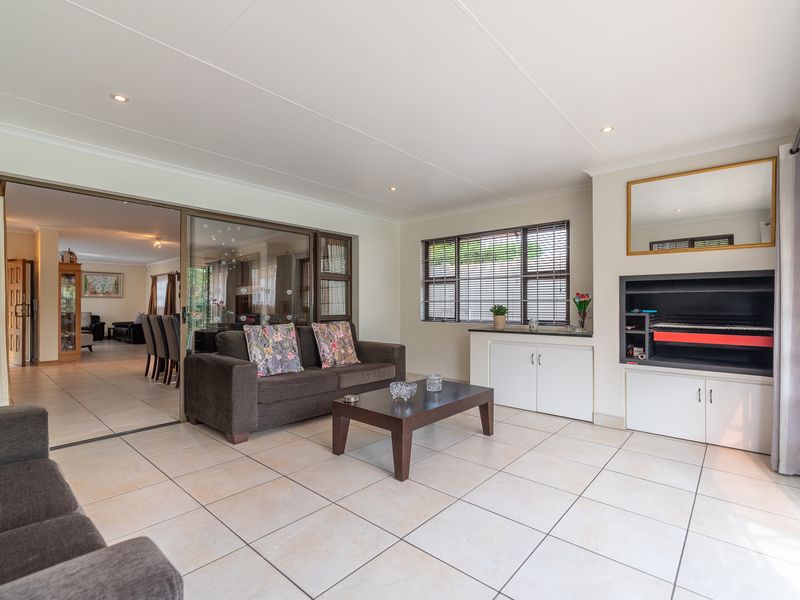 Spacious living room featuring tiled flooring, recessed lighting, built-in cabinetry, and a fireplace, with seamless flow through sliding doors to the adjacent dining area.