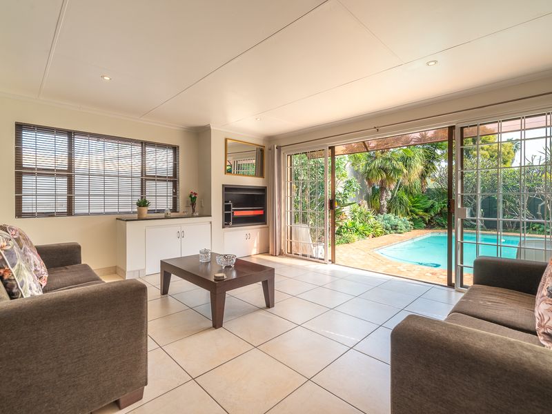 Bright living room featuring tiled floors, a built-in fireplace, and large sliding doors providing seamless access to the outdoor pool area.