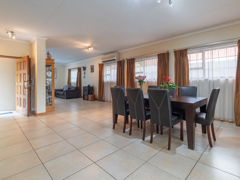 Spacious open-plan living and dining area featuring neutral tiled flooring, air conditioning, and direct access to the main entrance.