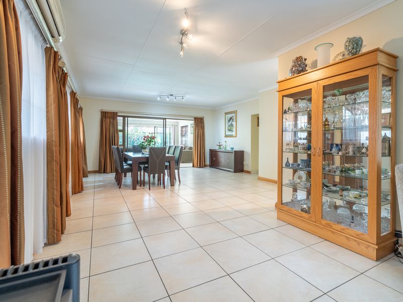 Spacious open-plan living and dining area featuring neutral tiled flooring, large sliding doors providing natural light, and integrated air conditioning.