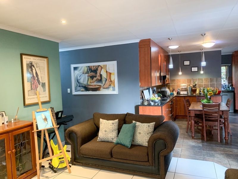 Open-plan living and kitchen area featuring tiled flooring, modern cabinetry, granite countertops, and a combination of recessed and pendant lighting.
