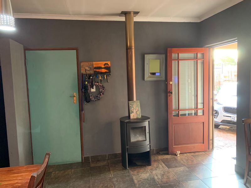Living area featuring a freestanding fireplace, tiled flooring, and direct access to the exterior through a timber door.