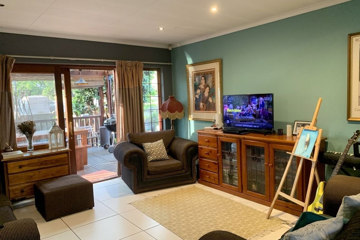 A comfortable living room featuring tiled flooring, recessed lighting, and a sliding glass door providing direct access to an outdoor patio area.