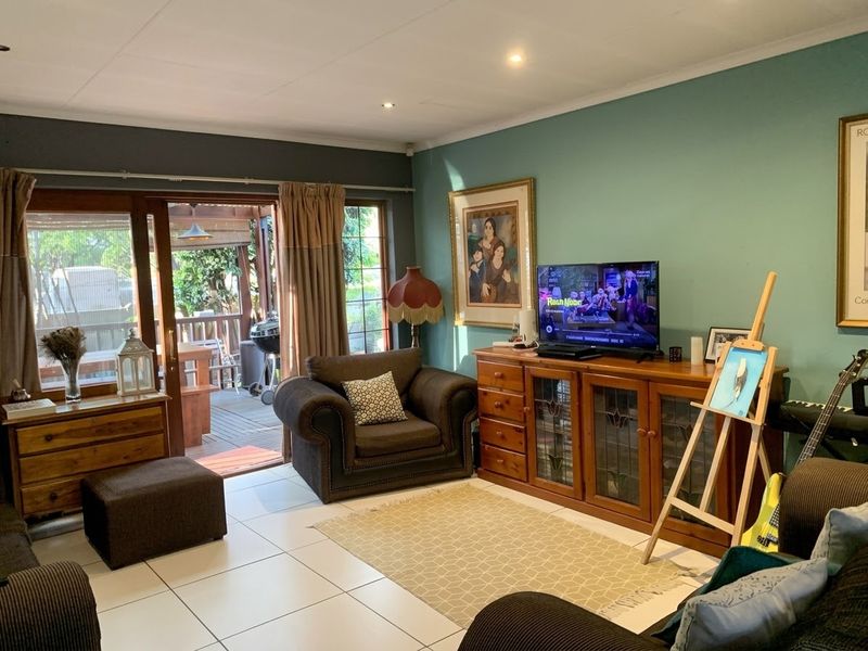 A comfortable living room featuring tiled flooring, recessed lighting, and a sliding glass door providing direct access to an outdoor patio area.