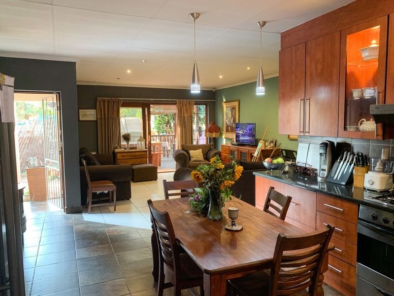 Open-plan living and dining area featuring a kitchen with wood-finish cabinetry, granite countertops, and direct access to an outdoor patio through sliding doors.