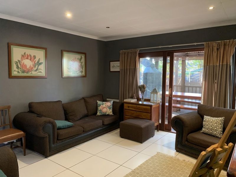 A comfortable living room featuring tiled flooring, recessed downlighting, and a sliding glass door providing direct access to the outdoor patio area.
