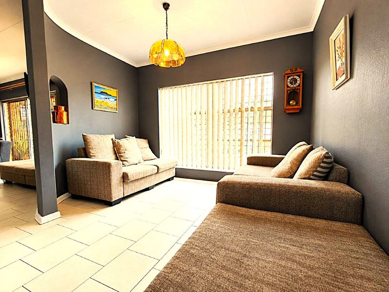 A living room featuring tiled flooring, vertical blinds, and a decorative arched wall niche, providing a functional and comfortable living space.