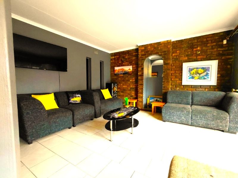 A living room featuring an exposed brick wall, tiled flooring, and an arched doorway, providing a cozy and character-filled space.