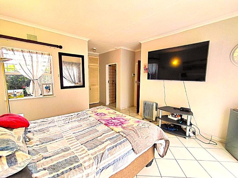 A bedroom featuring tiled flooring and built-in storage cupboards, providing a functional living space with natural light from the window.