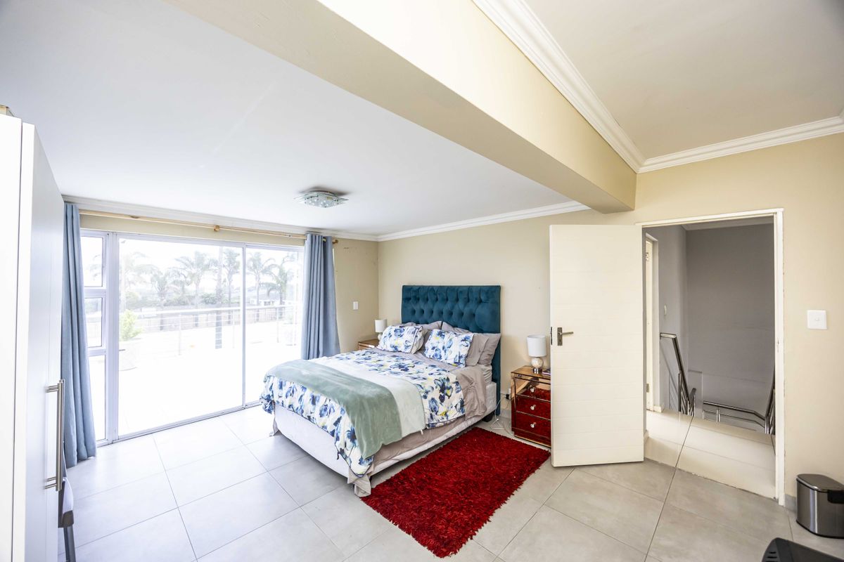 Spacious bedroom featuring tiled flooring, crown molding, and a large sliding glass door providing access to an outdoor balcony area.