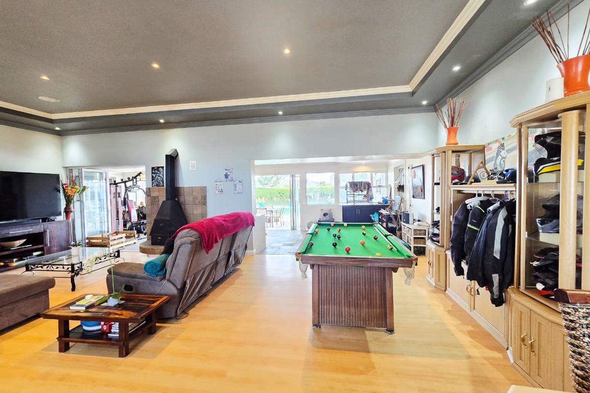 Spacious open-plan living area featuring a tray ceiling, recessed lighting, a central fireplace with tiled surround, and direct access to the outdoor patio.