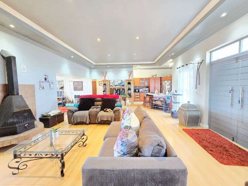 Spacious open-plan living area featuring a modern freestanding fireplace, recessed ceiling lighting, and a functional kitchen with an island, creating a bright, cohesive living space.