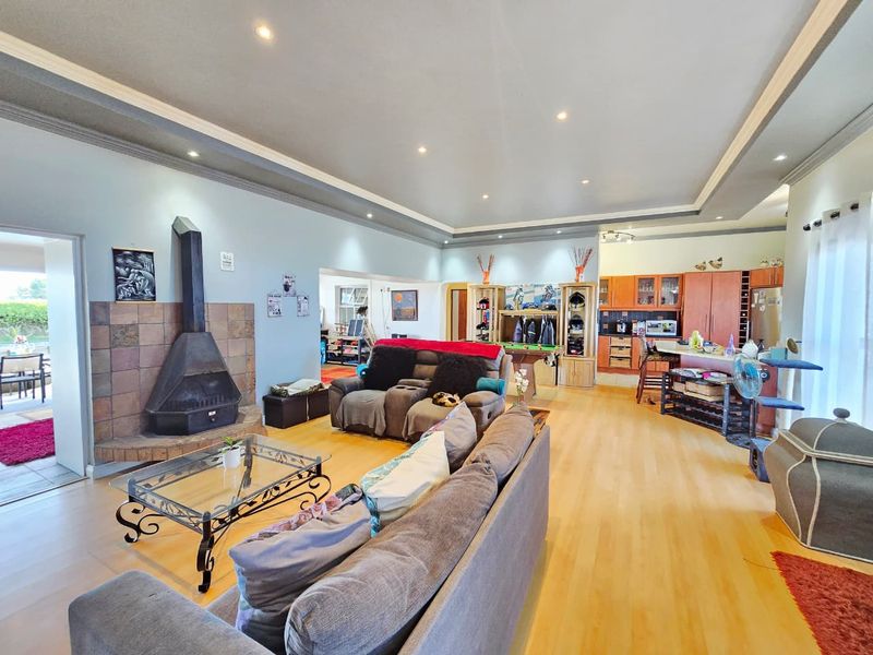Spacious open-plan living area featuring a tiled fireplace, recessed ceiling with downlights, and a functional kitchen with ample cabinetry and an island.