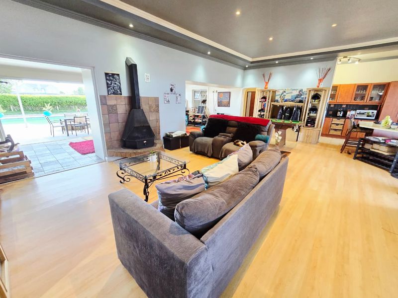 Spacious open-plan living area featuring a freestanding fireplace, laminate flooring, and seamless flow to the outdoor patio and pool area.