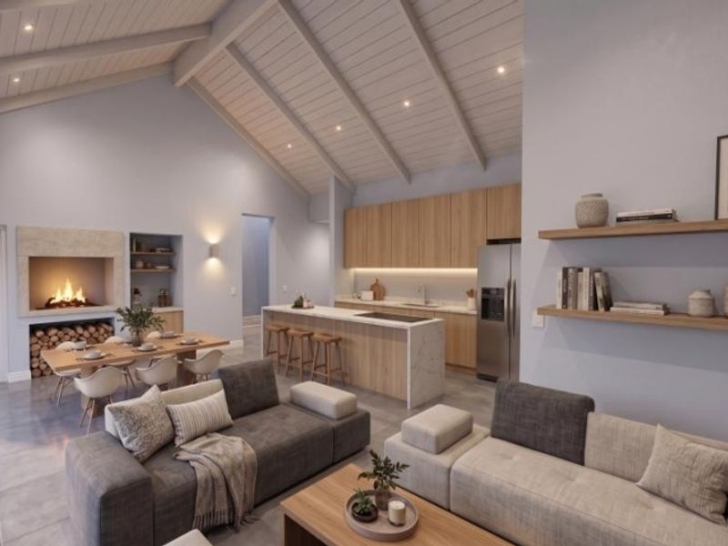 Spacious open-plan living area featuring a vaulted ceiling with exposed beams, a modern kitchen with island, and a cozy built-in fireplace.