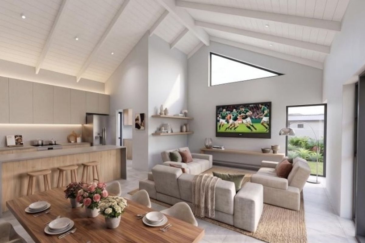 Spacious open-plan living area featuring a modern kitchen with island, vaulted ceilings with exposed rafters, and seamless flow to the outdoor patio.