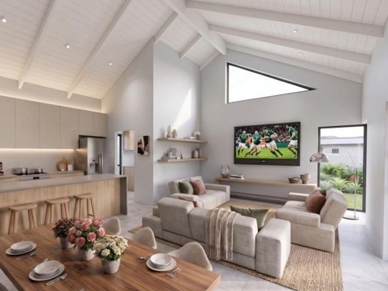 Spacious open-plan living area featuring a modern kitchen with island, vaulted ceilings with exposed rafters, and seamless flow to the outdoor patio.