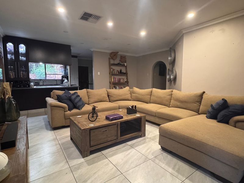 Spacious open-plan living area featuring tiled flooring, recessed lighting, and an integrated kitchen space with dark cabinetry.
