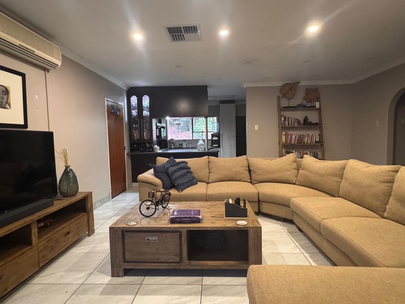 Spacious open-plan living area featuring tiled flooring, recessed lighting, and a split-system air conditioner, seamlessly connecting to the kitchen space.