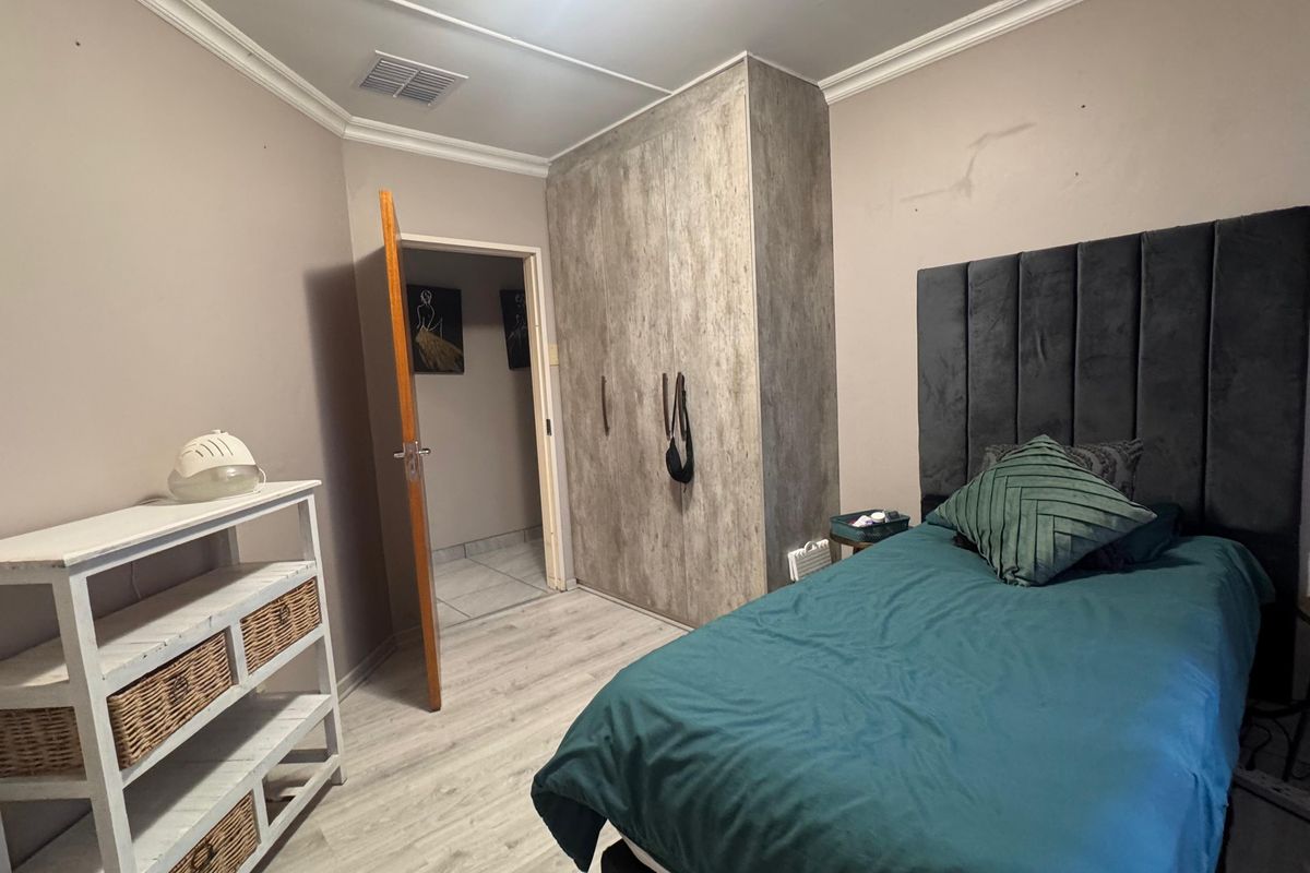 A bedroom featuring laminate flooring, built-in cupboards with a textured finish, and coving detail. The room requires minor wall maintenance.