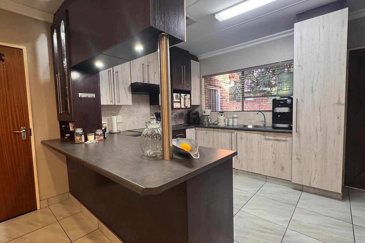 A functional kitchen featuring two-tone cabinetry, dark laminate countertops, a breakfast bar, and tiled flooring with ample storage space.
