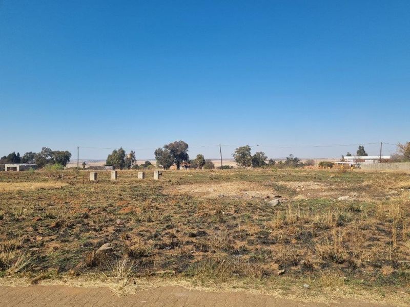 A view of a vacant residential plot of land featuring natural terrain and utility infrastructure, ready for development.