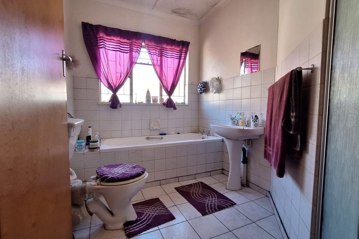A dated bathroom featuring a pedestal basin, built-in bathtub, and shower enclosure, requiring cosmetic updates and ceiling repairs.