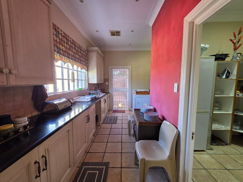 A functional scullery area featuring built-in cabinetry, granite countertops, and tiled flooring, providing additional workspace and storage adjacent to the main kitchen.