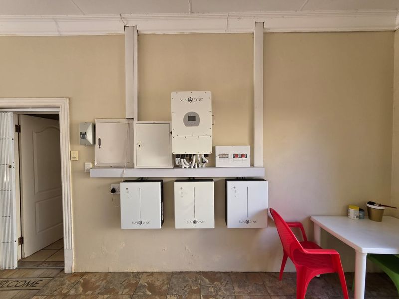 Utility area featuring a professional solar power installation with a Sunsynk inverter and three integrated battery units mounted on the wall.