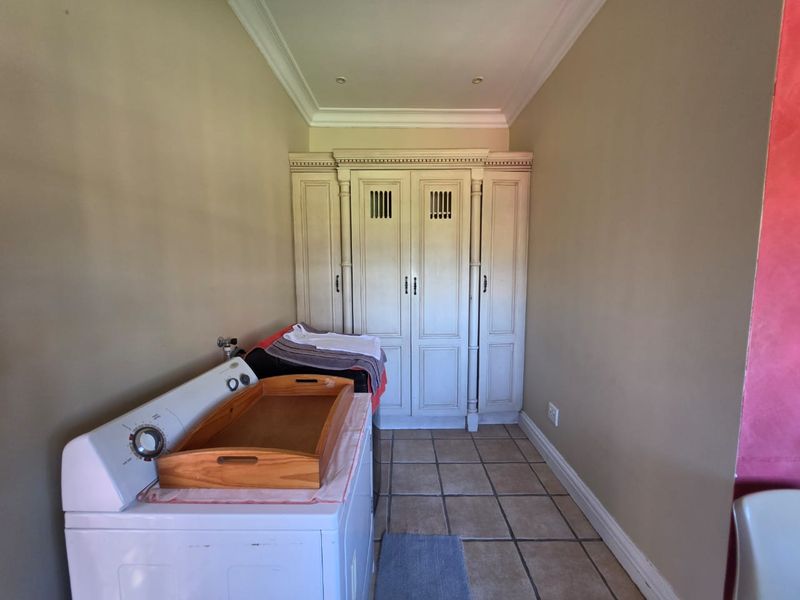 A functional laundry area featuring built-in cabinetry, tiled flooring, and recessed ceiling lighting, providing practical storage and utility space.