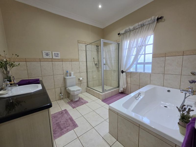 A well-maintained bathroom featuring a built-in vanity, a separate shower enclosure, and a bathtub with neutral tiled finishes throughout.