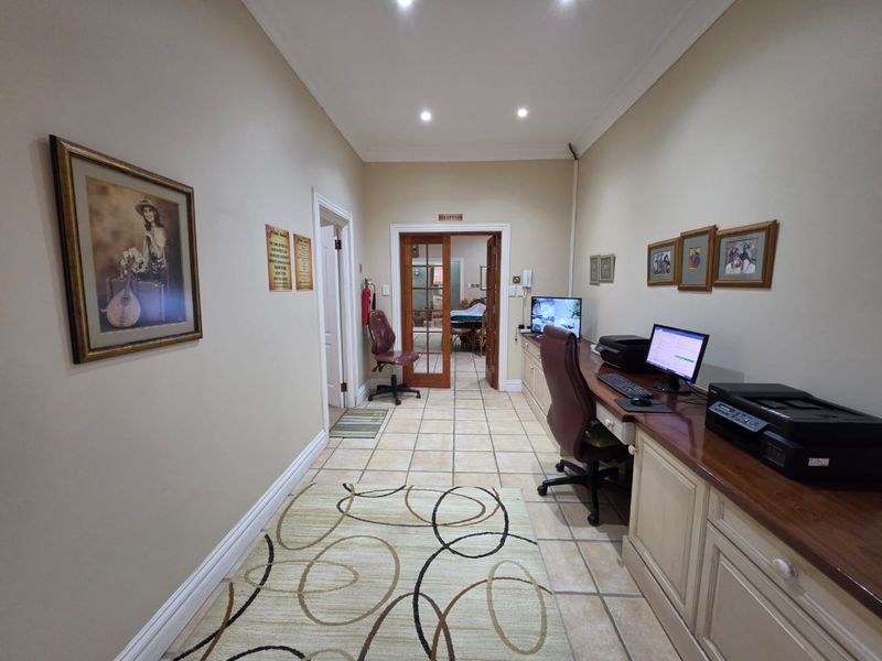 A functional reception area featuring tiled flooring, recessed lighting, and a built-in wooden desk, providing a professional welcome space for the guest house.