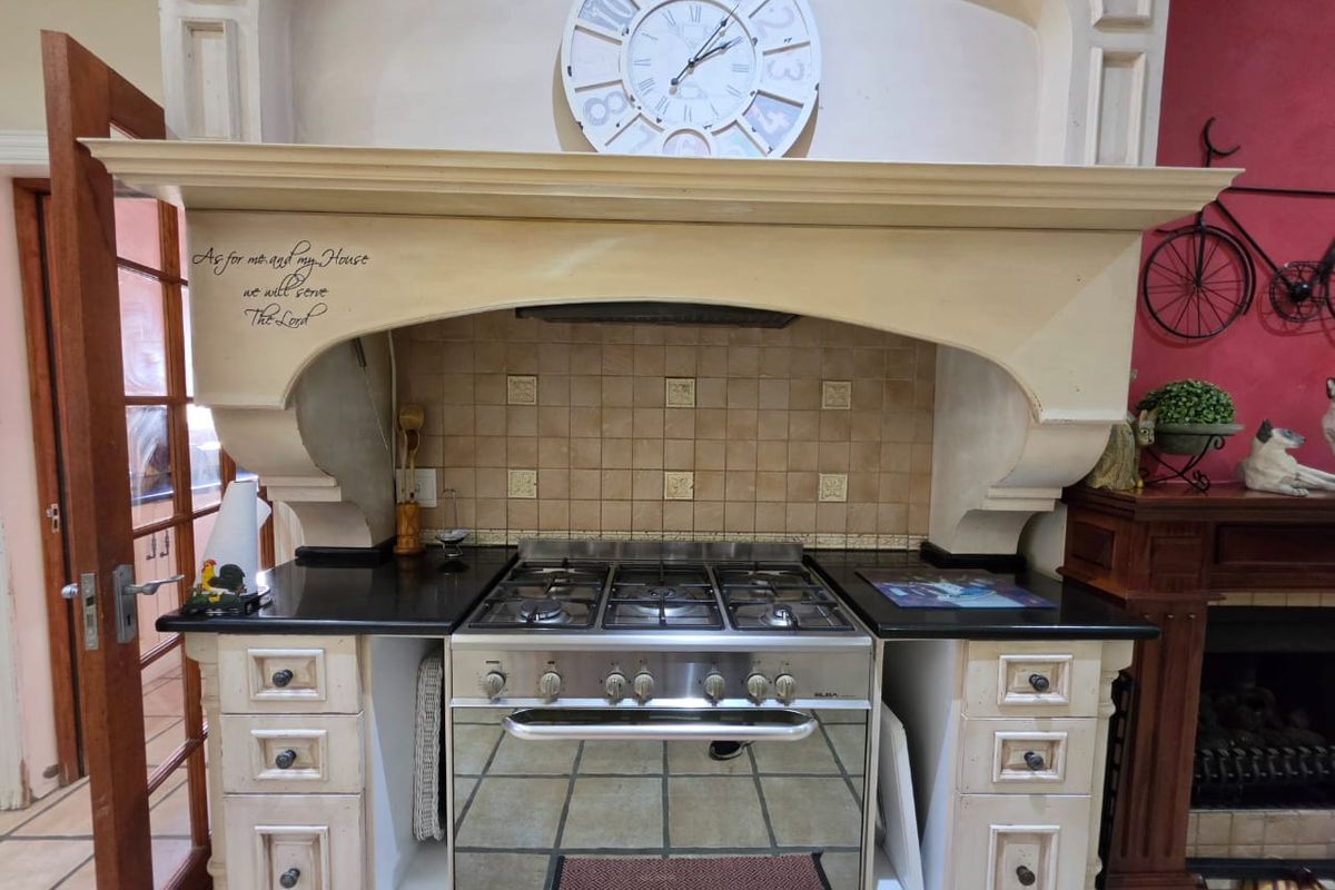 A traditional kitchen featuring a built-in gas stove, oven, and decorative range hood with granite countertops and tiled backsplash.