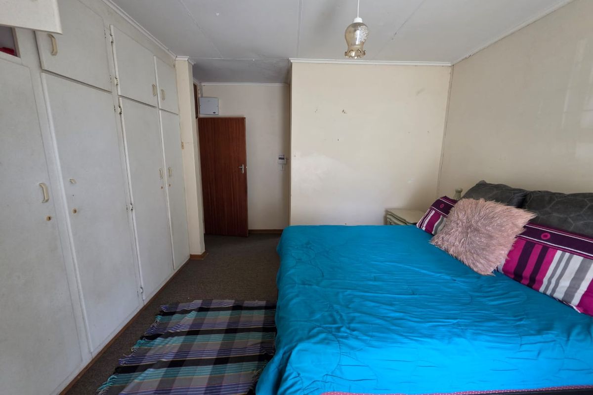 A bedroom featuring built-in cupboards and carpeted flooring, offering a functional space with potential for cosmetic updates to enhance its appeal.