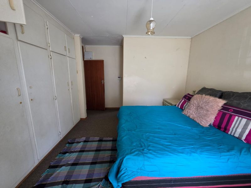 A bedroom featuring built-in cupboards and carpeted flooring, offering a functional space with potential for cosmetic updates to enhance its appeal.
