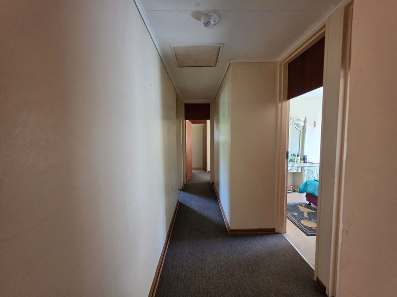 A functional hallway connecting multiple rooms, featuring neutral wall finishes, carpeted flooring, and a ceiling access hatch.