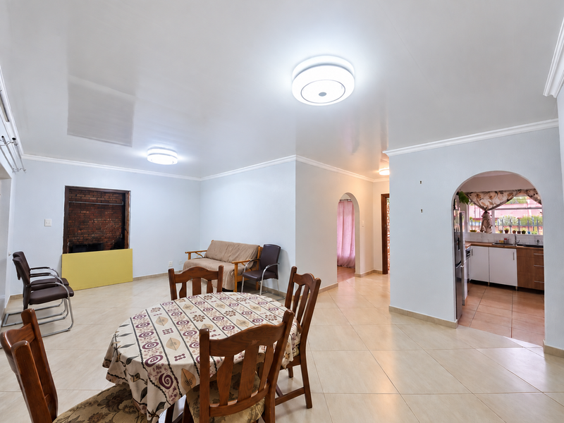 Spacious open-plan living and dining area featuring tiled floors, arched doorways, and a built-in fireplace, offering a versatile layout for family living.