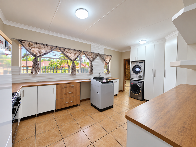 A functional laundry room featuring built-in cabinetry, laminate countertops, ceramic tile flooring, and dedicated space for laundry appliances.
