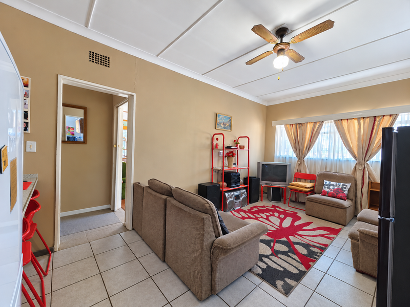 Open plan living area featuring tiled flooring and a ceiling fan, with direct access to adjacent rooms.