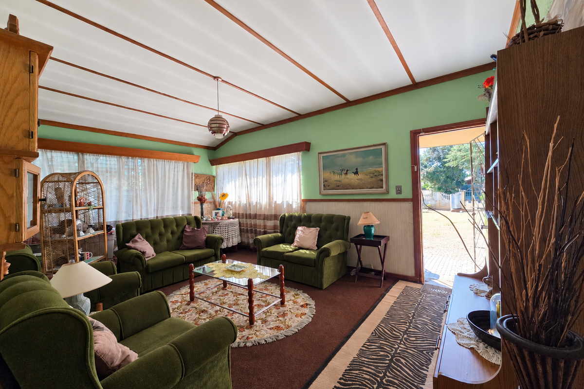 A dated living room featuring exposed beam ceilings, wainscoting, and direct access to the exterior, offering potential for a modern renovation.