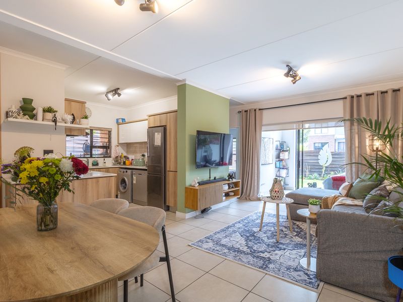 A bright open-plan living, dining, and kitchen area featuring tiled floors, modern cabinetry, and large sliding doors leading to an outdoor space.