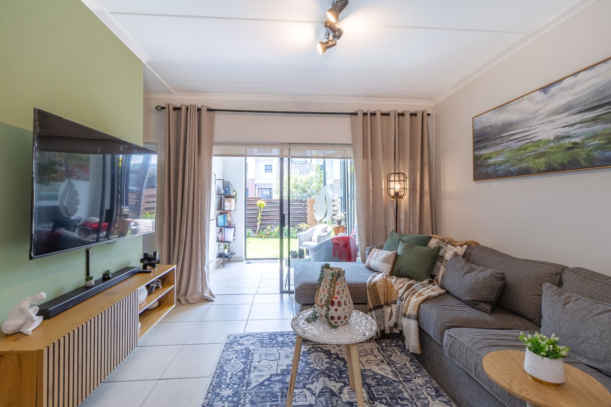 A well-maintained living room featuring tiled flooring, an accent wall, and large sliding glass doors that provide direct access to the outdoor patio area.